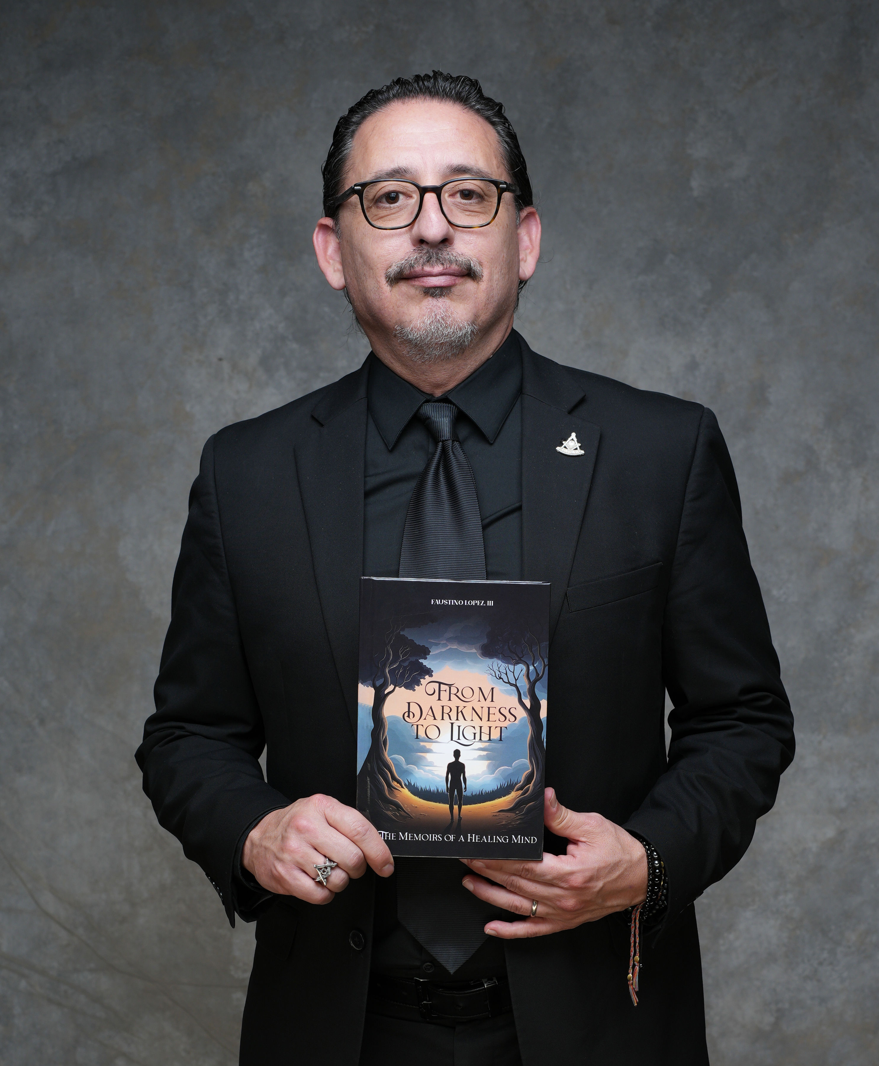Faustino Lopez III holding his memoir, From Darkness to Light